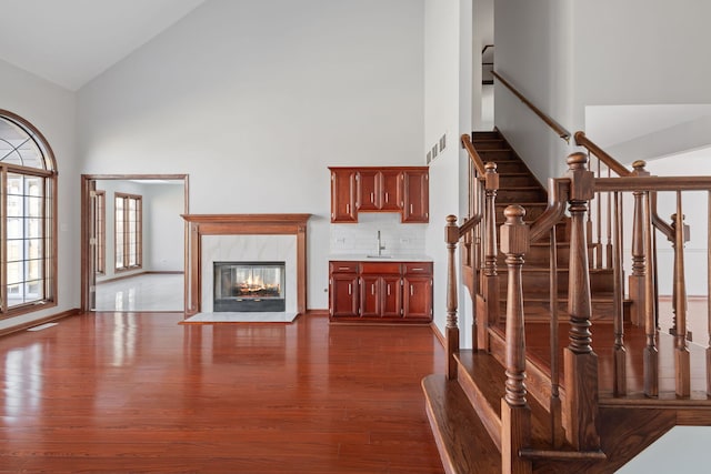 interior space with a high end fireplace, visible vents, dark wood finished floors, high vaulted ceiling, and a sink