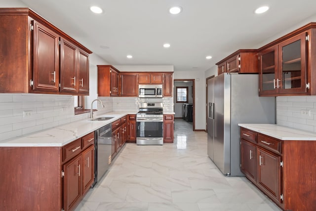 kitchen featuring marble finish floor, a sink, recessed lighting, appliances with stainless steel finishes, and glass insert cabinets