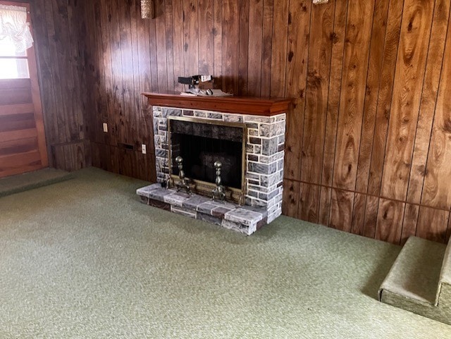 living area featuring a stone fireplace, wood walls, and carpet floors