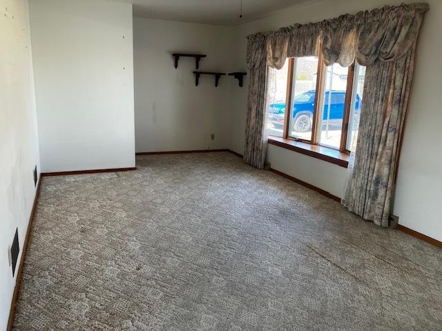 carpeted spare room featuring visible vents and baseboards