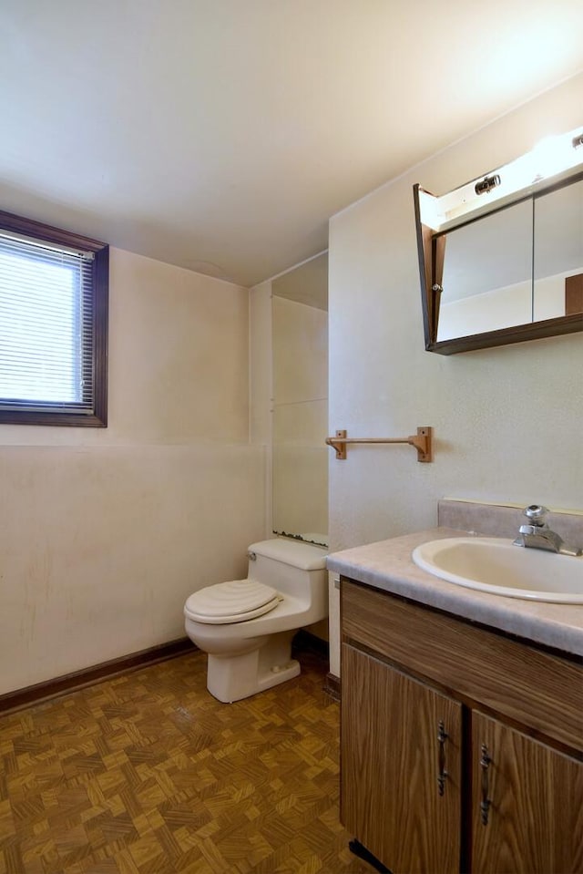 bathroom featuring toilet, vanity, and baseboards