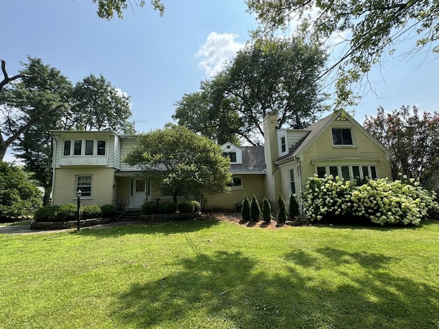 view of front of house with brick siding, a chimney, and a front lawn