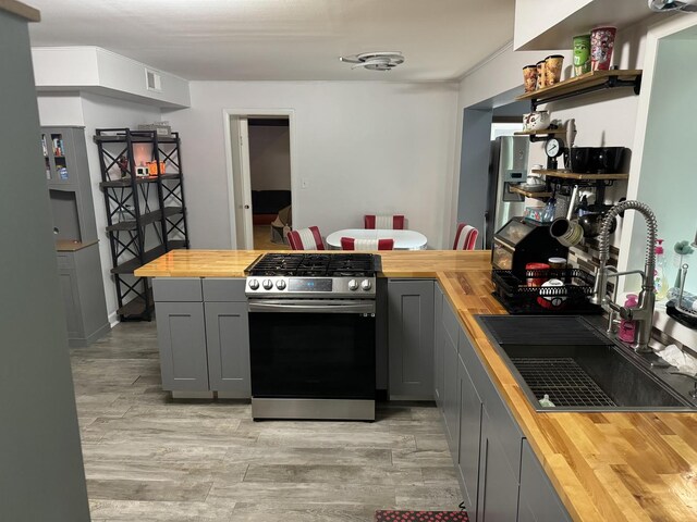 kitchen featuring gray cabinets, stainless steel appliances, wood counters, and a sink