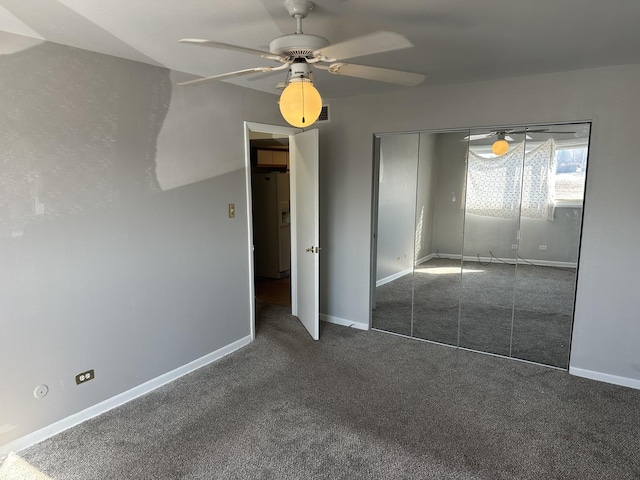 unfurnished bedroom with a ceiling fan, a closet, carpet floors, white fridge with ice dispenser, and baseboards