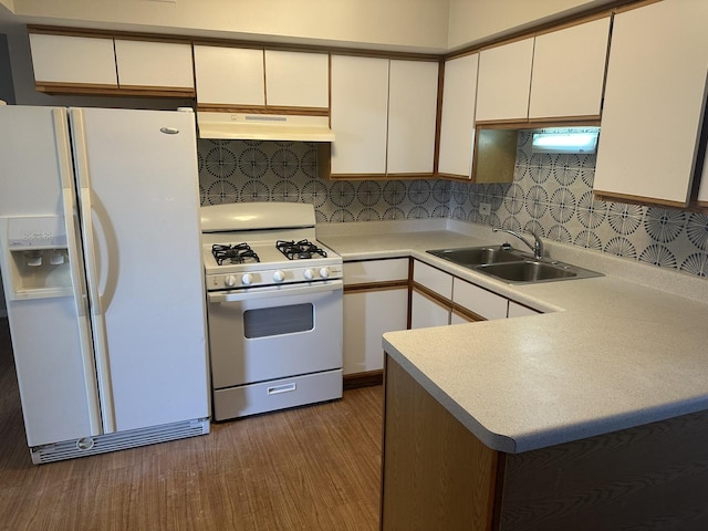 kitchen featuring under cabinet range hood, light countertops, wood finished floors, white appliances, and a sink