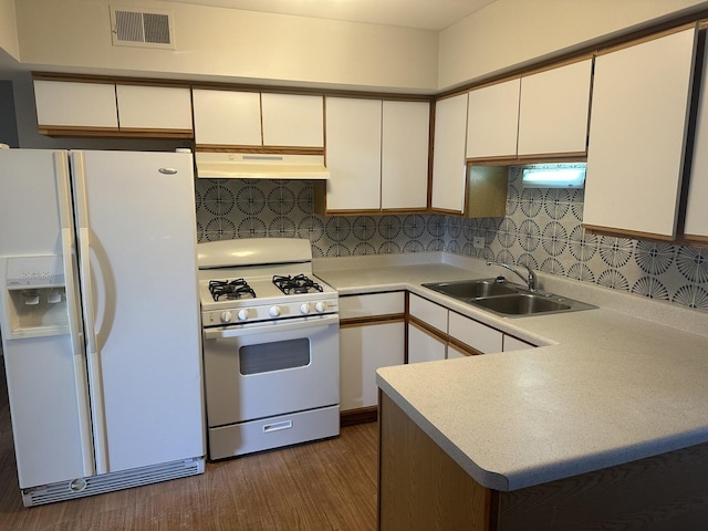 kitchen featuring visible vents, a sink, under cabinet range hood, white appliances, and decorative backsplash