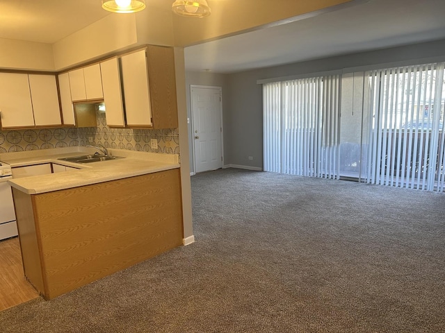 kitchen featuring a sink, white cabinetry, carpet flooring, light countertops, and decorative backsplash