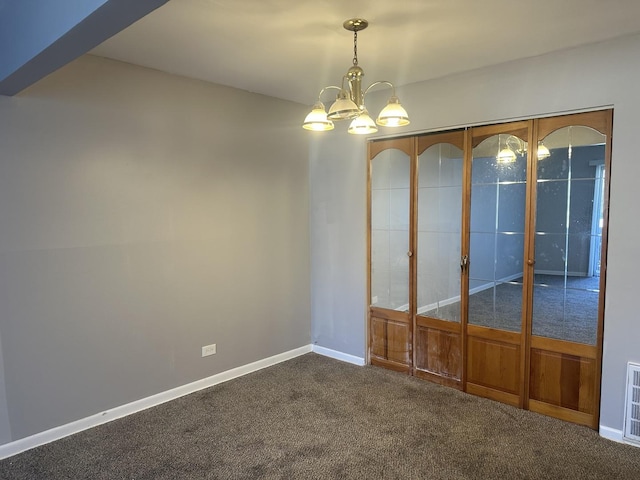 empty room featuring a chandelier, visible vents, dark carpet, and baseboards