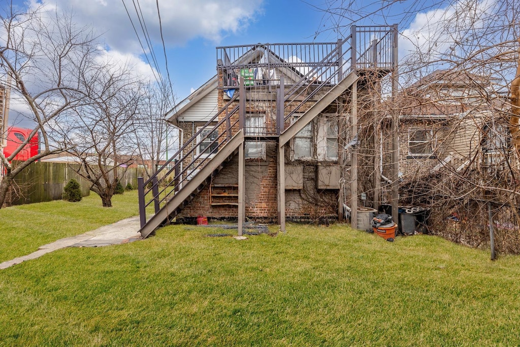 back of house with a wooden deck, a lawn, and stairs