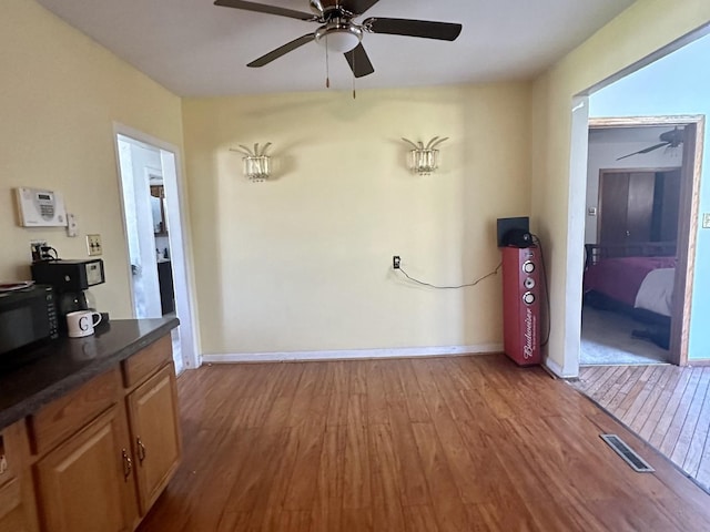 spare room featuring a ceiling fan, wood finished floors, visible vents, and baseboards