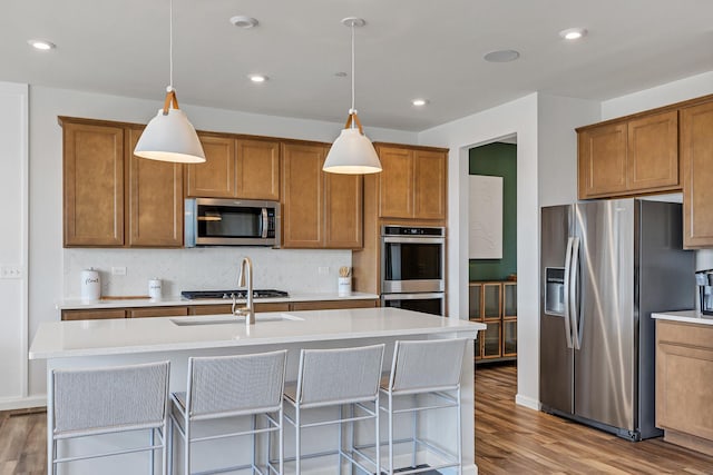 kitchen featuring brown cabinets, tasteful backsplash, appliances with stainless steel finishes, and wood finished floors