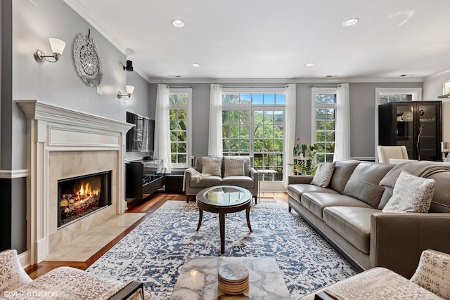 living area featuring recessed lighting, wood finished floors, ornamental molding, and a high end fireplace