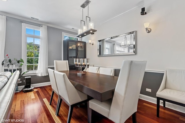 dining space featuring crown molding, wood finished floors, visible vents, and baseboards