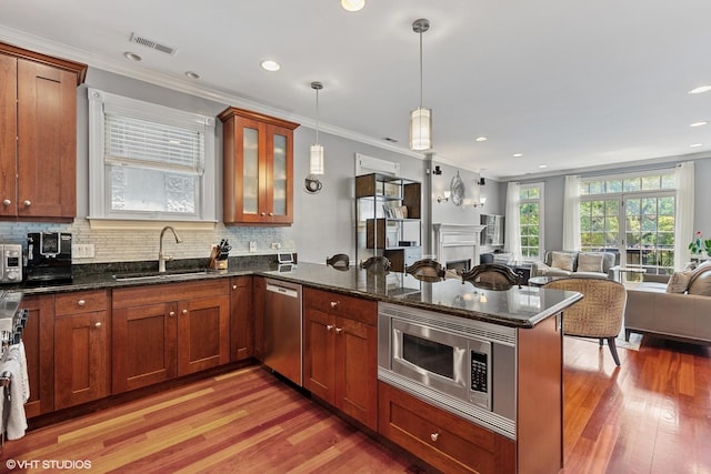 kitchen featuring visible vents, open floor plan, appliances with stainless steel finishes, a peninsula, and a sink