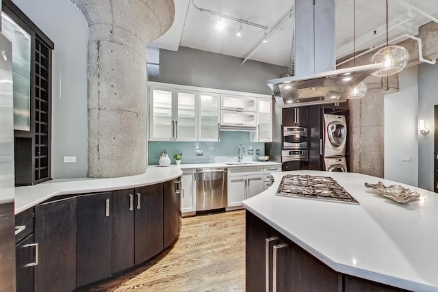 kitchen featuring a sink, light countertops, stacked washer / drying machine, appliances with stainless steel finishes, and white cabinetry