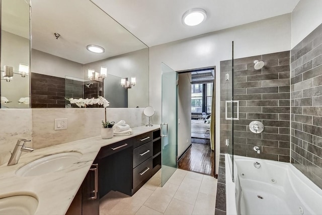 full bath with double vanity, a combined bath / shower with jetted tub, tile patterned floors, and a sink