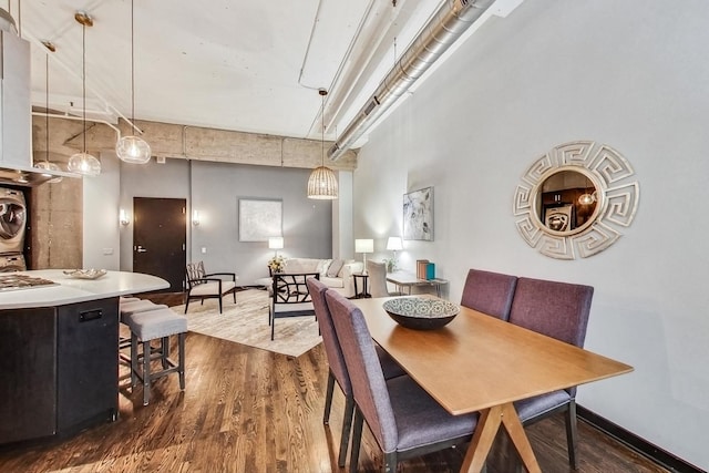 dining room featuring stacked washer and clothes dryer, baseboards, dark wood-type flooring, and a towering ceiling