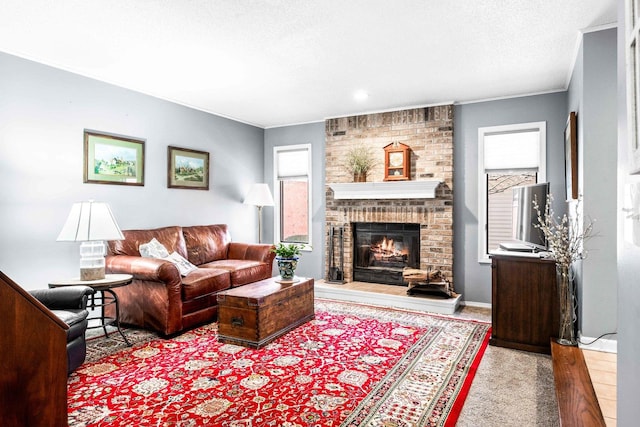 living area with wood finished floors, baseboards, ornamental molding, a textured ceiling, and a brick fireplace