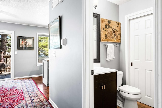 bathroom with baseboards, toilet, vanity, wood finished floors, and a textured ceiling