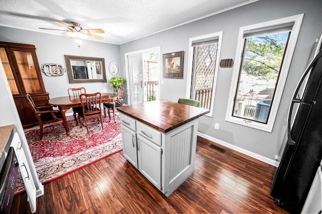 kitchen with visible vents, dark wood-type flooring, butcher block countertops, a textured ceiling, and freestanding refrigerator