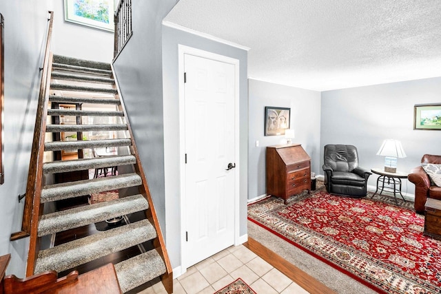 stairway with tile patterned floors, baseboards, and a textured ceiling