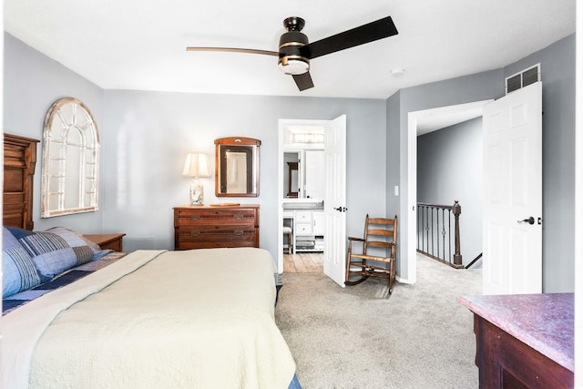 carpeted bedroom with connected bathroom, visible vents, and ceiling fan