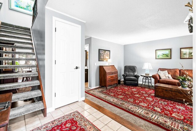 living room with light tile patterned floors, stairway, a textured ceiling, and baseboards