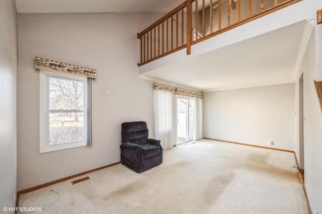 sitting room with visible vents, carpet floors, baseboards, and a towering ceiling