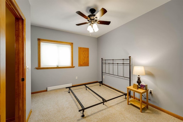 carpeted bedroom with ceiling fan, a baseboard heating unit, and baseboards