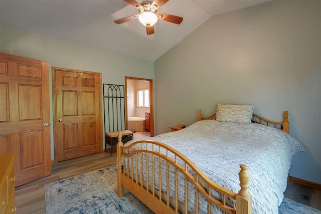 bedroom with lofted ceiling, wood finished floors, ensuite bathroom, and ceiling fan