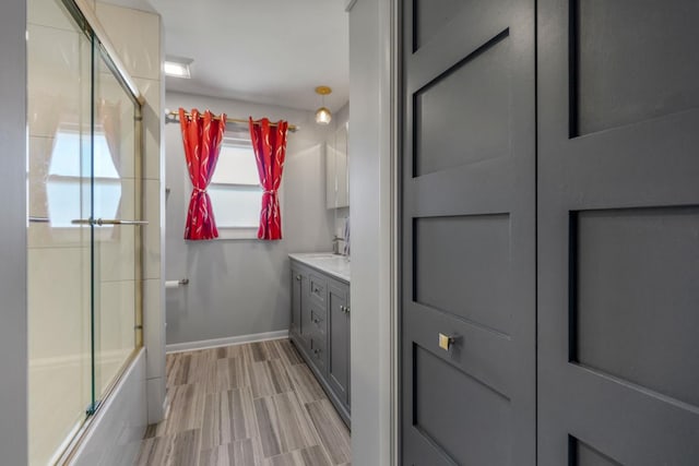 full bath with vanity, wood tiled floor, baseboards, and enclosed tub / shower combo