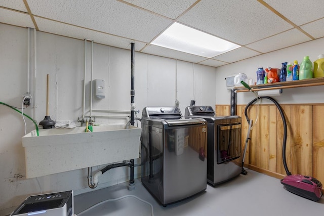 clothes washing area with laundry area, a sink, a wainscoted wall, and separate washer and dryer