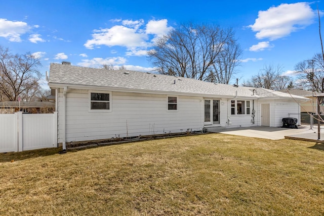 back of house featuring a lawn, a shingled roof, a patio, and fence