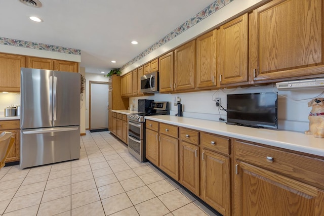 kitchen with light tile patterned floors, appliances with stainless steel finishes, brown cabinetry, and light countertops