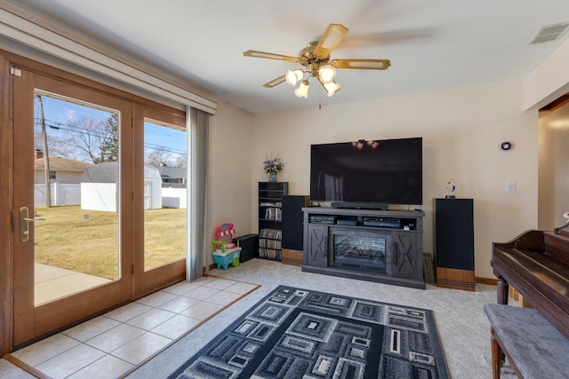 living area featuring tile patterned flooring, visible vents, carpet, and a ceiling fan