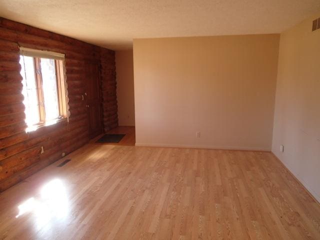 spare room with visible vents, light wood-type flooring, and a textured ceiling