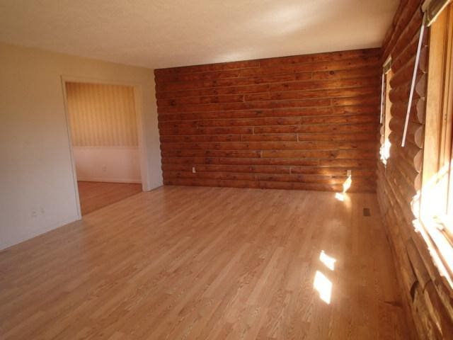 unfurnished room with rustic walls and light wood-style flooring