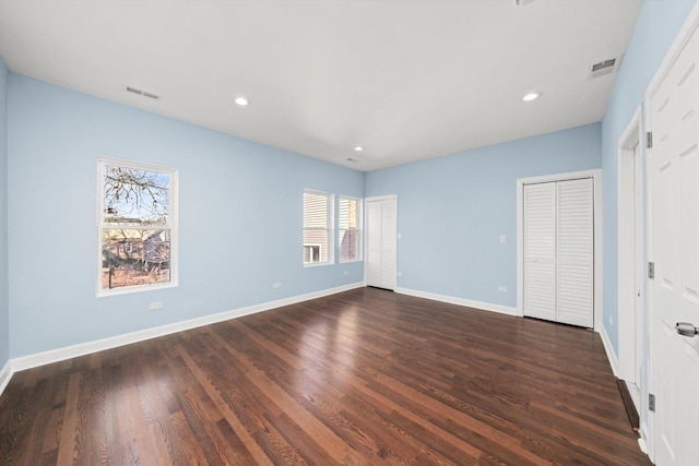 unfurnished bedroom with visible vents, baseboards, and dark wood-style floors