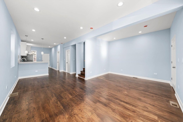 unfurnished living room featuring visible vents, baseboards, stairs, recessed lighting, and dark wood-style floors