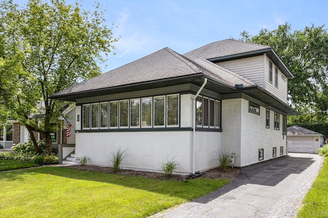 view of side of property with a lawn, a shingled roof, an outdoor structure, and stucco siding