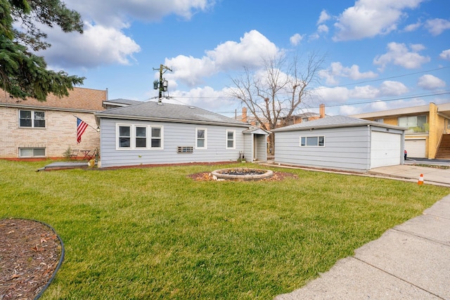 back of house with an outbuilding, a yard, a garage, and an outdoor fire pit