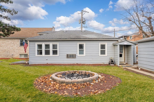 back of house featuring a yard, a fire pit, and roof with shingles