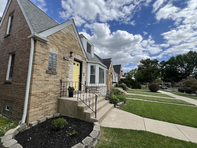 view of side of property featuring a lawn and brick siding