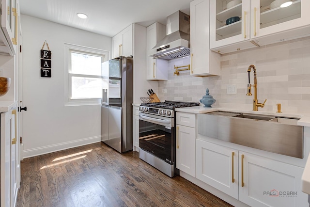 kitchen with dark wood finished floors, stainless steel appliances, light countertops, white cabinetry, and wall chimney range hood