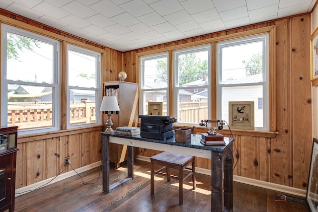 office space with dark wood-style floors, wooden walls, and baseboards