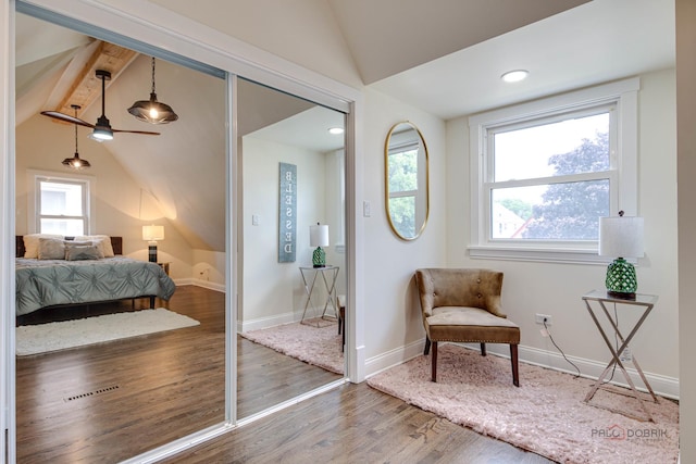 bedroom with baseboards, multiple windows, wood finished floors, and vaulted ceiling