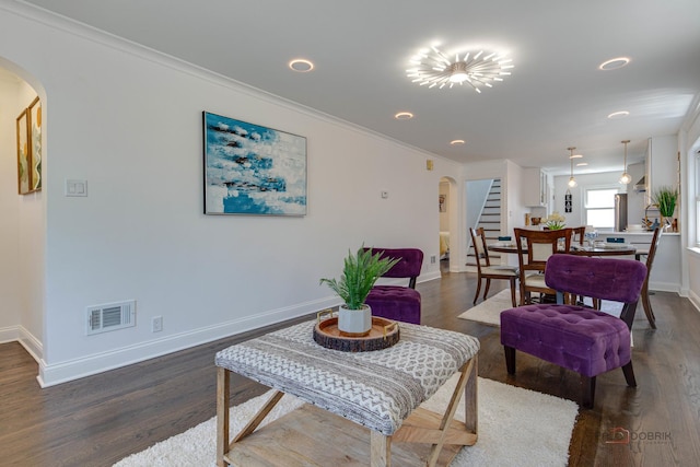 living area with dark wood-type flooring, visible vents, arched walkways, and baseboards