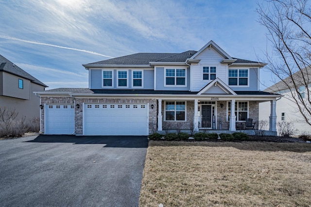 view of front facade with aphalt driveway, a garage, covered porch, and stone siding