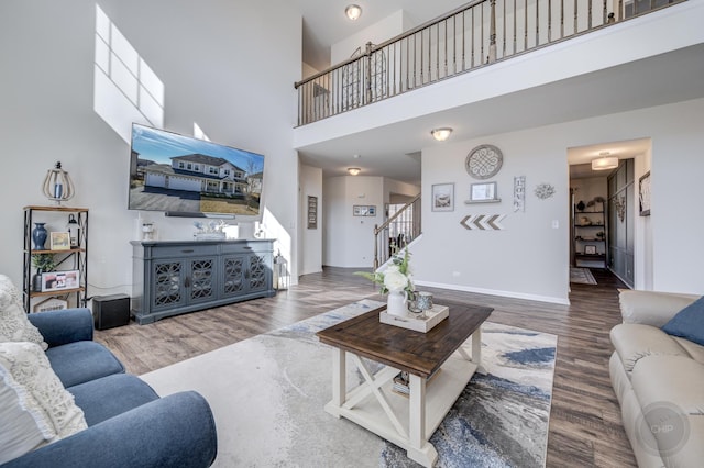 living room with a high ceiling, stairway, wood finished floors, and baseboards