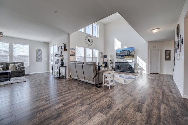 living room with wood finished floors, baseboards, and a towering ceiling